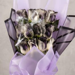 Bouquet of dark-tipped white roses wrapped in lavender paper