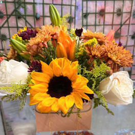 Sunflower and white rose bouquet in a pink gift bag