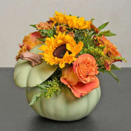 Orange and yellow flowers arranged in a pumpkin-shaped vase
