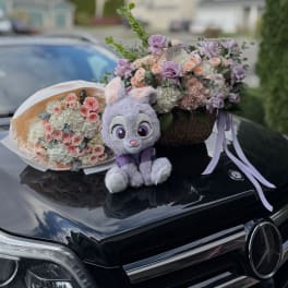 Two pastel flower arrangements with a plush bunny on a car hood