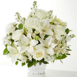 White roses and lilies arranged in a white basket.