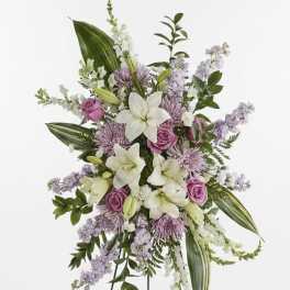 Standing floral spray with white lilies and pink roses on a black easel