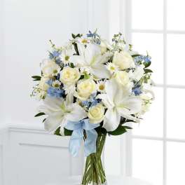 White lilies and roses with blue flowers in a glass vase