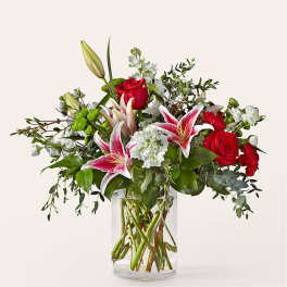Bouquet of red roses and pink lilies in a clear glass vase