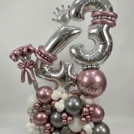 Silver and pink balloon arrangement with large number balloons and a crown topper