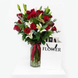 Red roses and white lilies in a glass vase with a ribbon