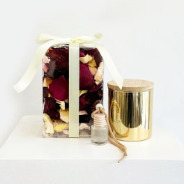 Gift set with dried rose petals, a gold candle tin, and a small bottle