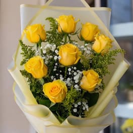 Bouquet of yellow roses with white baby's breath in pale wrapping