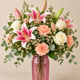 Pink lilies and white roses in a pink glass vase