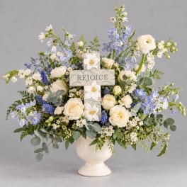 White and blue floral arrangement in a cream vase with a cross centerpiece