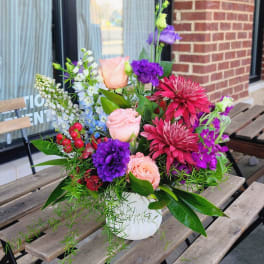 Mixed bouquet of pink, purple, and white flowers in a white vase