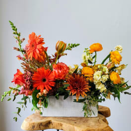 Bright mixed flower arrangement in a white rectangular vase