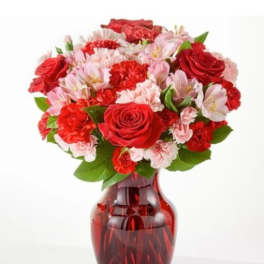 Red and pink flower bouquet in a red glass vase