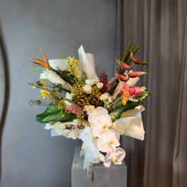 Tropical bouquet with white orchids, pink blooms, and orange bird-of-paradise flowers
