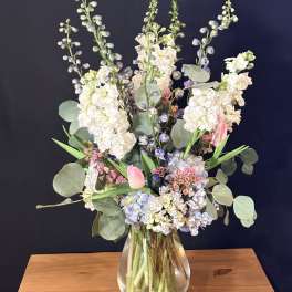 Tall pastel bouquet in a clear glass vase with pink tulips and white blooms