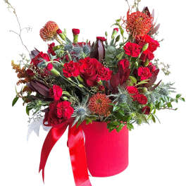 Red floral arrangement in a pink hatbox with ribbon