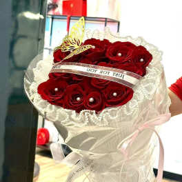 Bouquet of red roses wrapped in white lace and ribbon