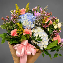 Bouquet of hydrangeas, roses, and small pink flowers with a pink ribbon