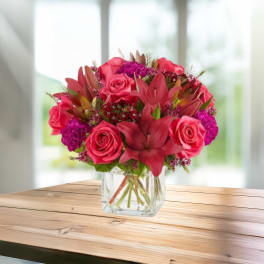 Pink roses and lilies arranged in a clear glass vase