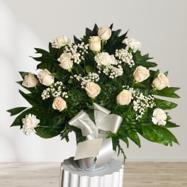 Cream roses and white carnations in a silver vase with a white ribbon