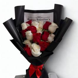 Bouquet of red and white roses wrapped in black paper with a red ribbon