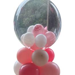 Pink and white balloons inside a clear balloon dome on a black base
