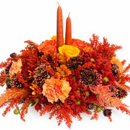 Orange and red floral centerpiece with two tall candles