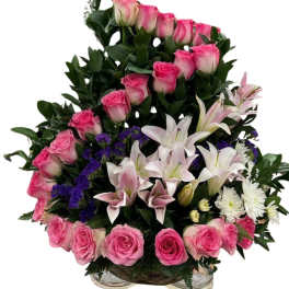 Pink roses and white lilies arranged in a basket with purple accents