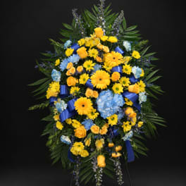 Large standing spray of yellow and blue flowers with ribbon accents
