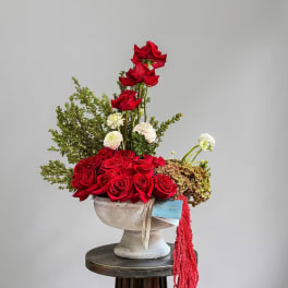 Red roses and white blooms arranged in a pedestal vase