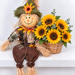 Scarecrow figure beside a basket of sunflowers