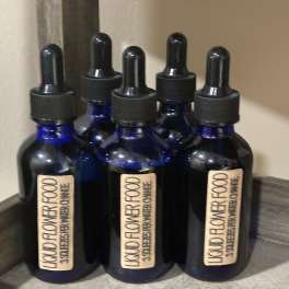 Five blue dropper bottles labeled liquid flower food