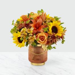 Orange and yellow mixed bouquet in a textured amber vase
