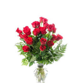 Tall arrangement of long-stemmed red roses in a clear glass vase