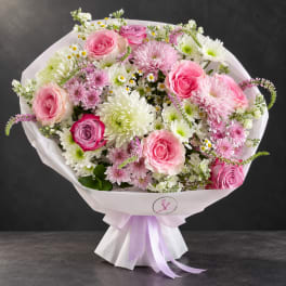 Pink and white bouquet of roses and chrysanthemums wrapped in pale paper