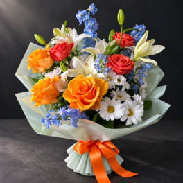 Bouquet of orange and red roses with white lilies and blue flowers
