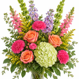 Colorful mixed bouquet in a clear glass vase with roses, hydrangea, and tall blooms