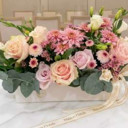Pink and cream flower arrangement in a white box with ribbon