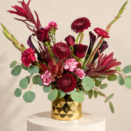 Red and pink mixed bouquet in a gold geometric vase
