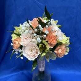 Bouquet of pale roses, peach carnations, and white filler flowers in a vase