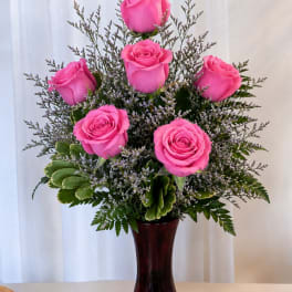 Pink roses arranged in a dark vase with greenery