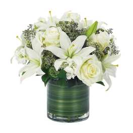 White lilies and roses arranged in a green glass vase