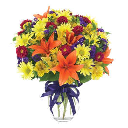 Mixed bouquet of orange lilies and yellow daisies in a glass vase with a purple ribbon