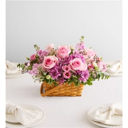 Pink roses and purple flowers arranged in a wicker basket