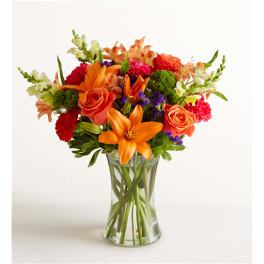 Orange lilies and roses in a clear glass vase