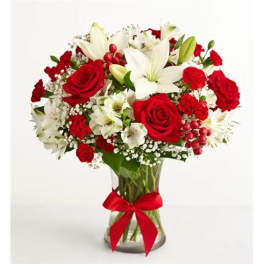 Bouquet of red roses and white lilies in a clear glass vase with a red ribbon
