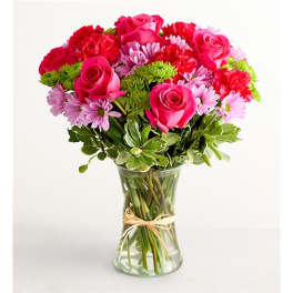 Pink roses and purple daisies in a clear glass vase
