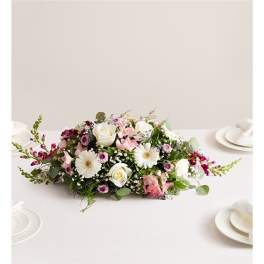 Low floral centerpiece with white and pink blooms on a table