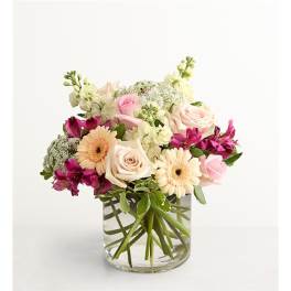 Mixed bouquet of roses, gerbera daisies, and alstroemeria in a clear glass vase