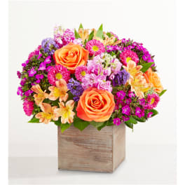Bright mixed bouquet with orange roses in a wooden cube vase